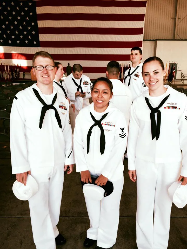 Eric in his Navy dress whites standing in front of the American flag