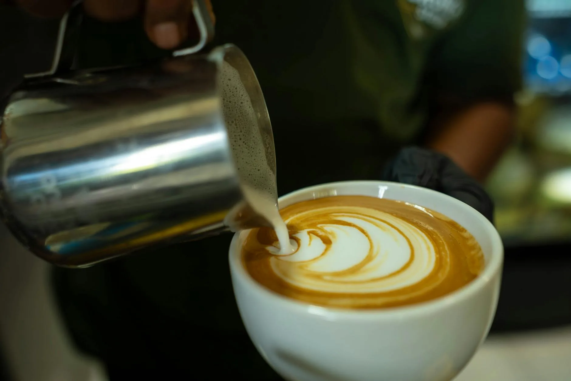 Barista creating latte art in a coffee cup at a catering event — The Roaring Bean