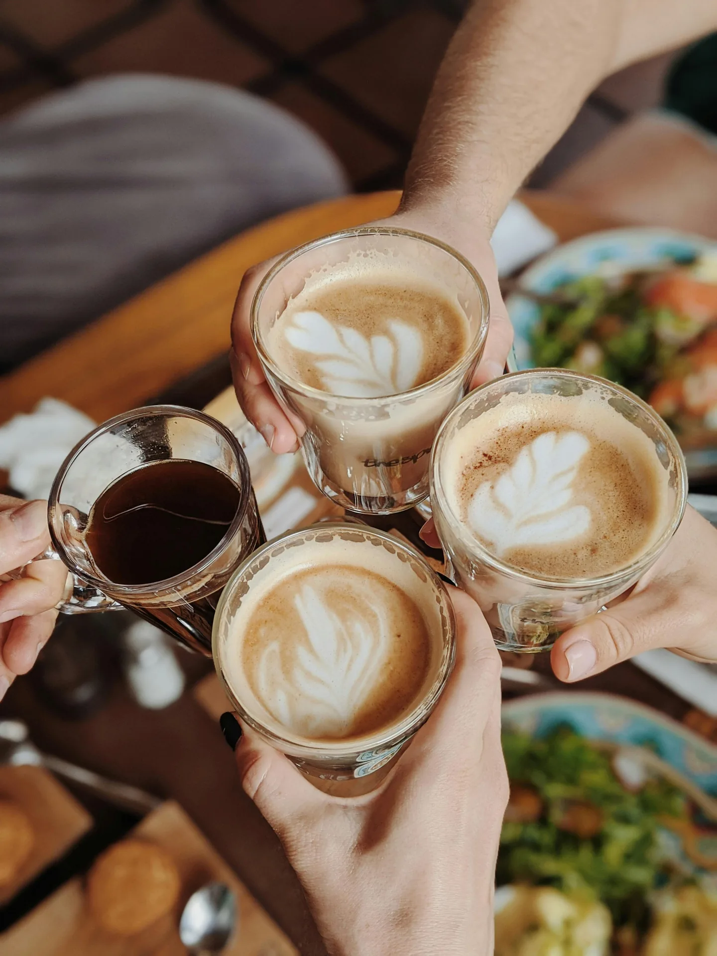 Friends raising glasses of specialty coffee drinks — celebrating great coffee from The Roaring Bean